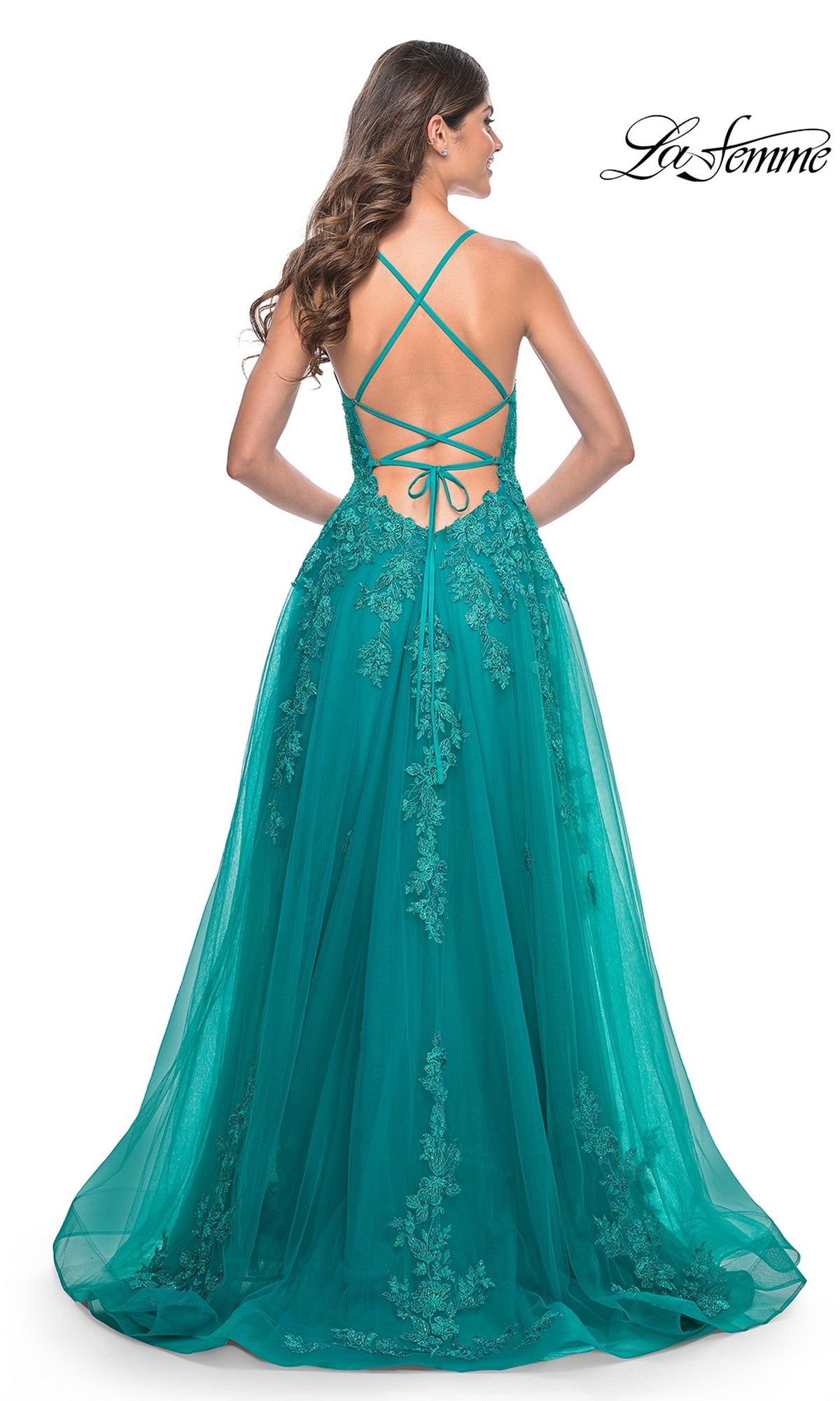 A woman stands facing away, wearing the La Femme Embroidered-Lace Long Prom Dress 32062 in teal with a crisscross open back and lace detailing.