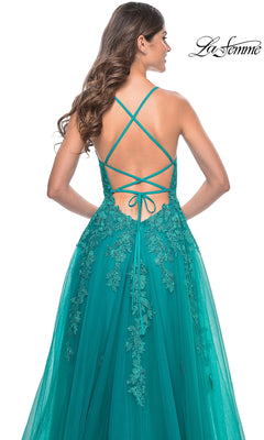 A woman stands with her back to the camera, wearing the teal La Femme Embroidered-Lace Long Prom Dress 32062, featuring a crisscross open back and floral lace details.