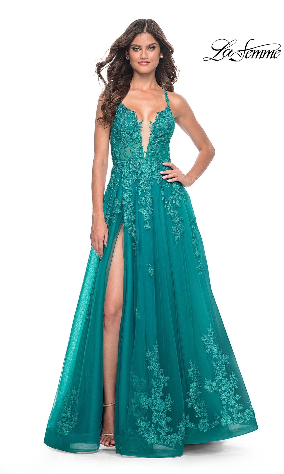 A woman wears the La Femme Embroidered-Lace Long Prom Dress 32062 in teal, featuring a floor-length design, embroidered lace details, a deep V neckline, thin straps, and a high leg slit.
