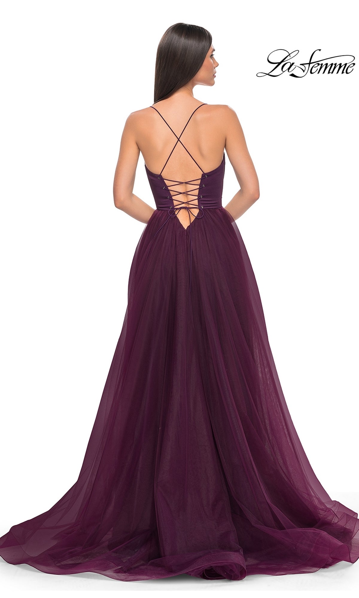 A woman in the La Femme Long Sweetheart Prom Ball Gown 32065, featuring a deep purple hue, lace-up open back, thin straps, and a flowing tulle overlay skirt, is shown elegantly from behind.