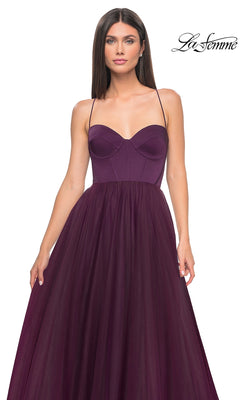 A woman wearing the La Femme Long Sweetheart Prom Ball Gown 32065 in deep purple, featuring a strapless fitted bodice and a flowing tulle skirt.