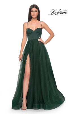 Woman wearing a dark green La Femme Long Sweetheart Prom Ball Gown 32065 with a fitted bodice, spaghetti straps, sleeveless design, thigh-high slit, and sheer overlay. "La Femme" logo appears in the upper right corner.