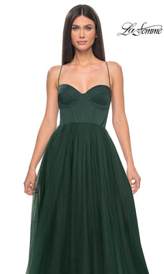 Woman wearing the La Femme Long Sweetheart Prom Ball Gown 32065 with spaghetti straps, a fitted bodice, and flowing dark green tulle skirt, standing against a plain white background.