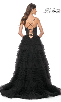 A woman stands against a white background wearing the La Femme 32071 Lace-Up Ruffle Long Prom Ball Gown, a black tiered tulle dress featuring an open lace-up back and sweetheart corset bodice.