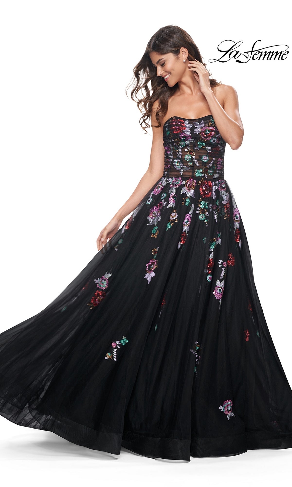 A woman wears the Le Femme Sequin-Floral Long Black Prom Dress 32072, featuring a strapless, sheer-bodice design with floral embroidery and a full tulle skirt. The brand name appears in the top right corner.