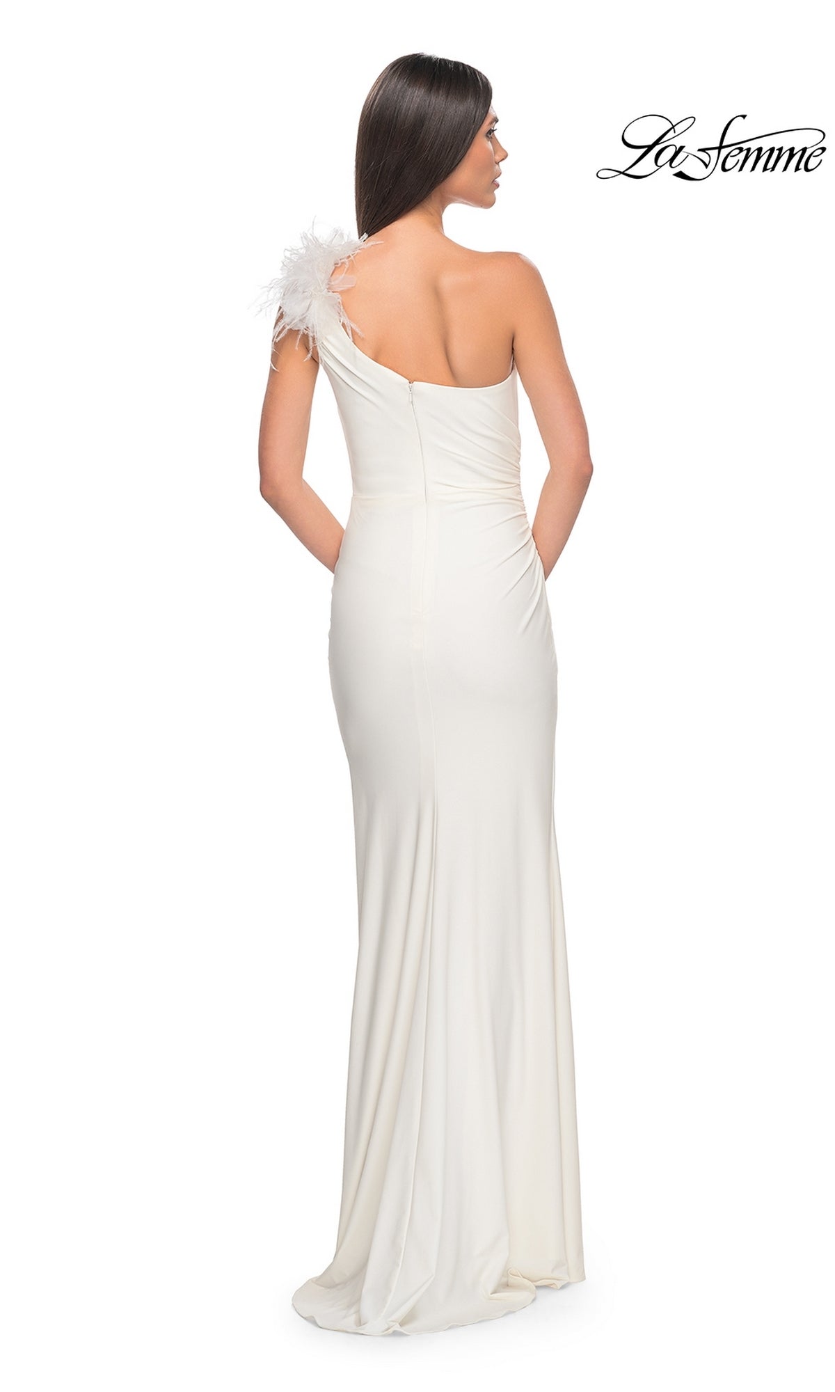 A woman stands with her back to the camera wearing the La Femme Feathered One-Shoulder Prom Dress 32076, a long white gown with feather detail on the strap; 