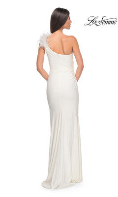 A woman stands with her back to the camera wearing the La Femme Feathered One-Shoulder Prom Dress 32076, a long white gown with feather detail on the strap; "La Femme" logo appears in the top right corner.