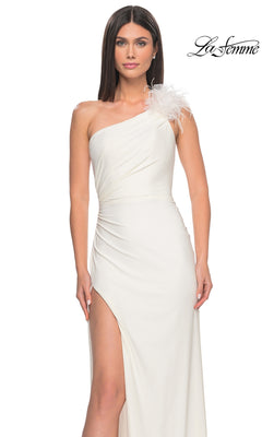 A woman poses against a white background in the La Femme Feathered One-Shoulder Prom Dress 32076, featuring a white long gown with a feathered strap and thigh-high slit. The La Femme logo is visible in the corner.