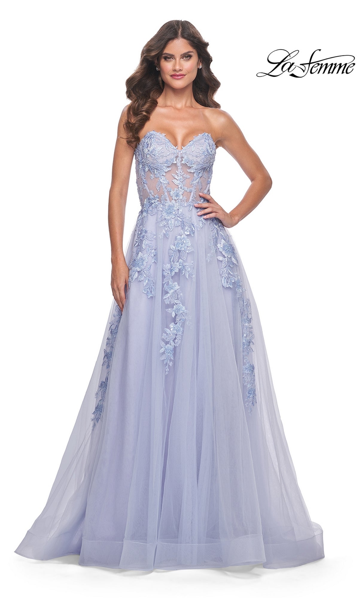A woman poses with hands on hips in the La Femme Strapless Long A-Line Corset Prom Dress 32082, featuring lavender floral lace appliqué and a sheer bodice. The La Femme logo appears in the upper right corner.