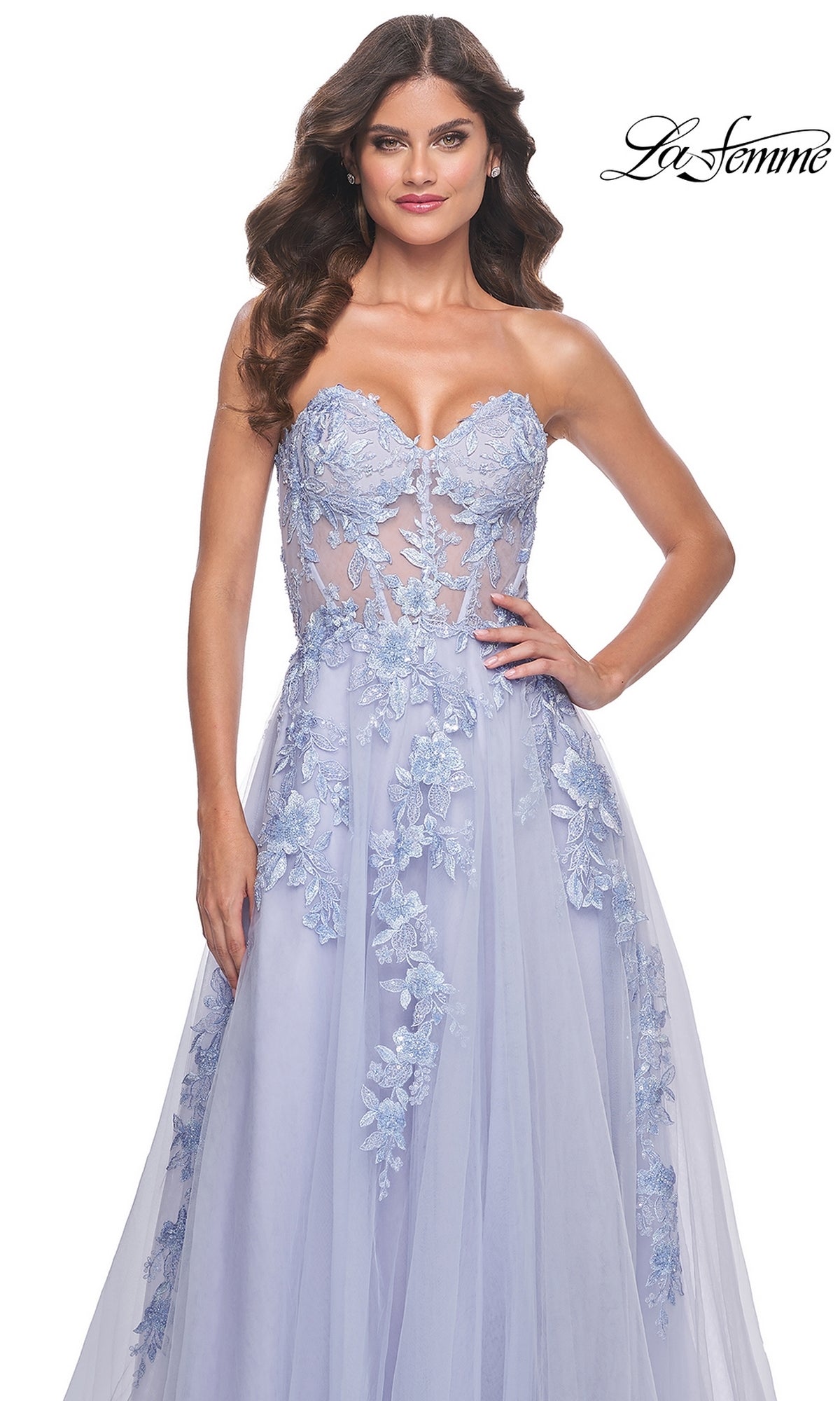 A woman wears the La Femme Strapless Long A-Line Corset Prom Dress 32082 in light blue, featuring floral lace appliqués, a sheer bodice, and an elegant flowing skirt. The La Femme logo is displayed in the top right corner.