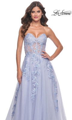 A woman wears the La Femme Strapless Long A-Line Corset Prom Dress 32082 in light blue, featuring floral lace appliqués, a sheer bodice, and an elegant flowing skirt. The La Femme logo is displayed in the top right corner.