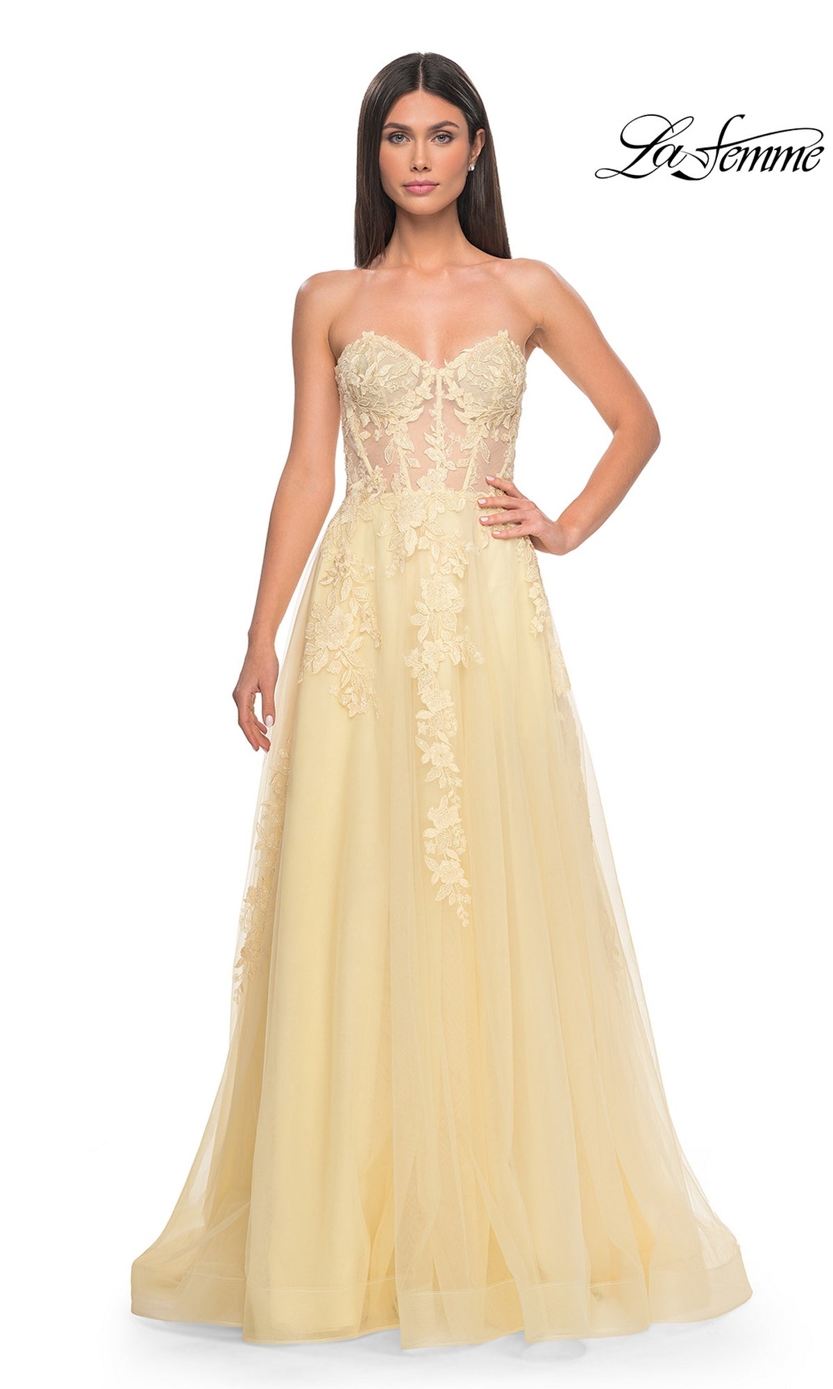 A woman wears the La Femme Strapless Long A-Line Corset Prom Dress 32082 in light yellow, featuring floral lace embroidery and a sheer corset bodice. The La Femme logo appears in the top right corner.
