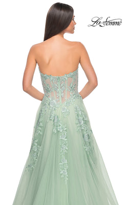 A woman faces away from the camera, wearing the La Femme Strapless Long A-Line Corset Prom Dress 32082 in light green, featuring floral lace embroidery and a sheer back. "La Femme" appears in the top right corner.
