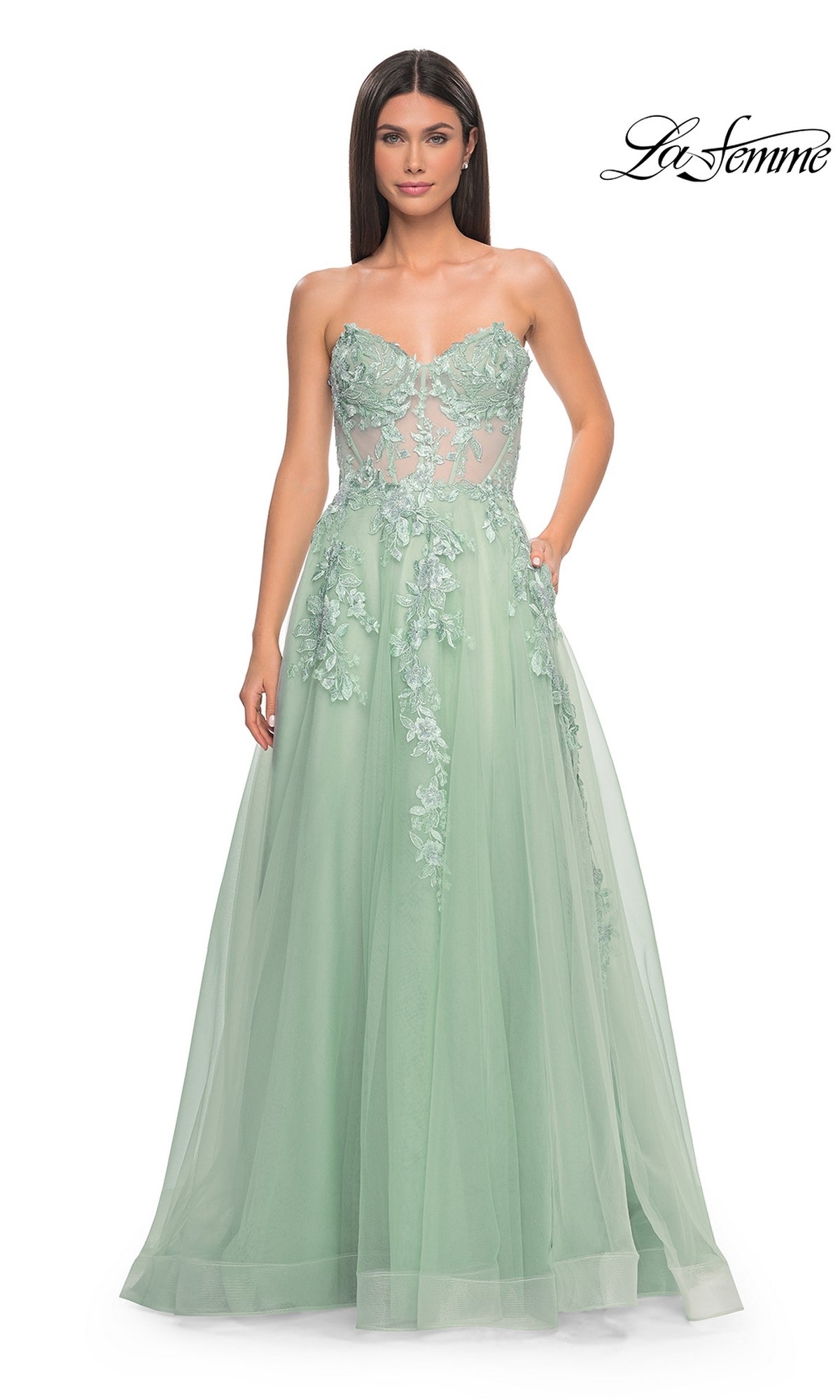 A woman wears the La Femme Strapless Long A-Line Corset Prom Dress 32082 in mint green, featuring floral appliqués and a sheer fitted bodice. The La Femme logo appears in the top right corner.
