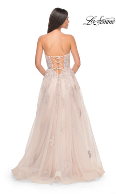 A woman with her back to the camera models the La Femme Backless Strapless Long Prom Dress 32084, a blush floor-length A-line gown featuring a lace-up back and floral embroidery.