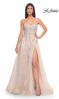 A woman models the La Femme Backless Strapless Long Prom Dress 32084 in blush, featuring silver floral embellishments and a high leg slit, standing against a white background.