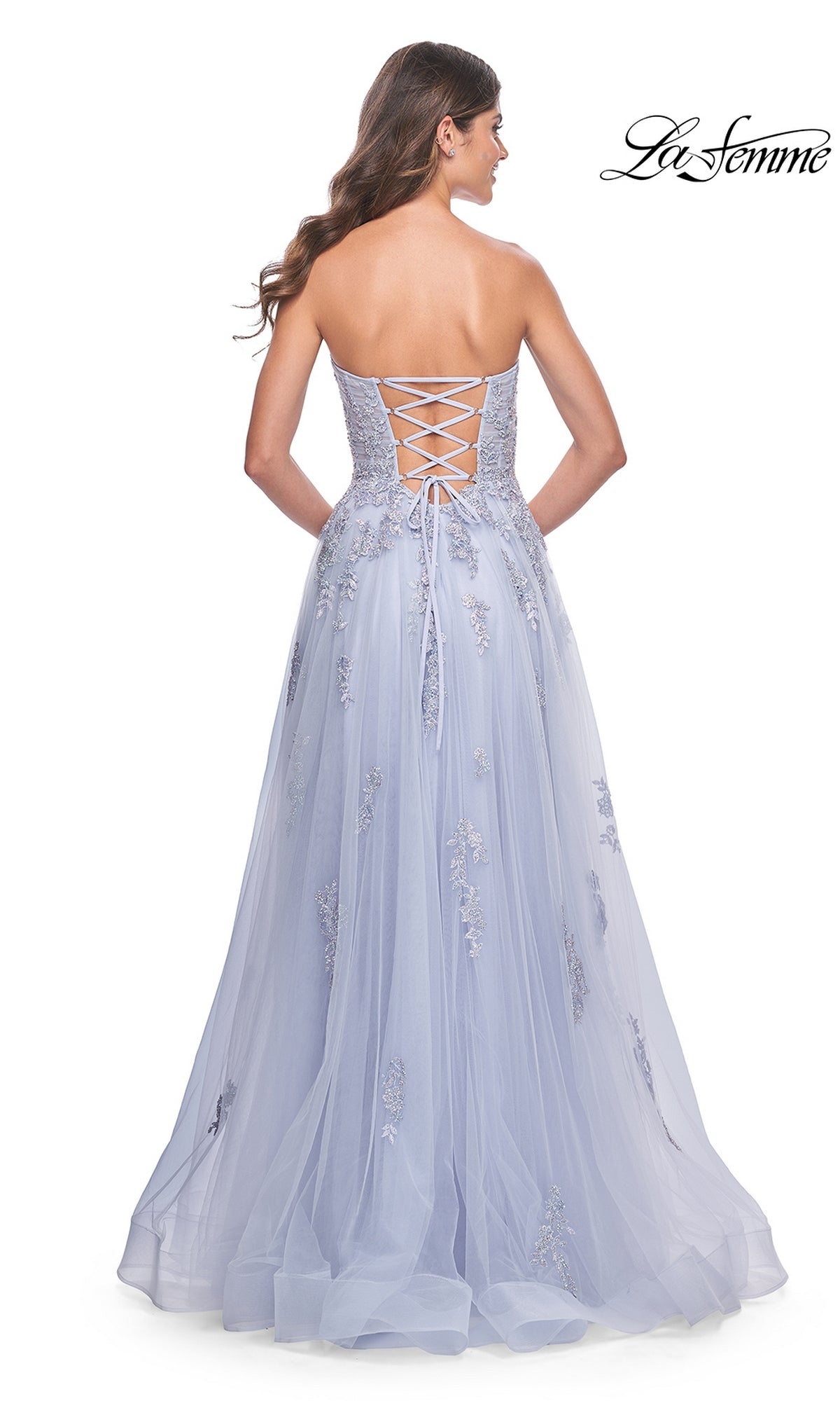 A woman faces away from the camera in the La Femme Backless Strapless Long Prom Dress 32084, an A-line lavender gown with floral embroidery and a lace-up back.