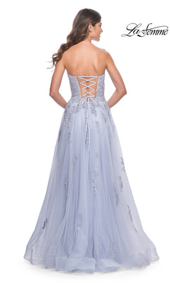 A woman faces away from the camera in the La Femme Backless Strapless Long Prom Dress 32084, an A-line lavender gown with floral embroidery and a lace-up back.