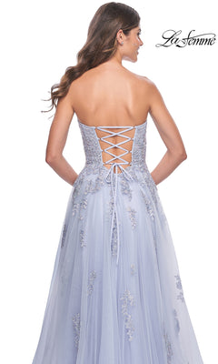 A woman faces away from the camera in the La Femme Backless Strapless Long Prom Dress 32084, a light blue A-line gown with floral embroidery and a lace-up back.