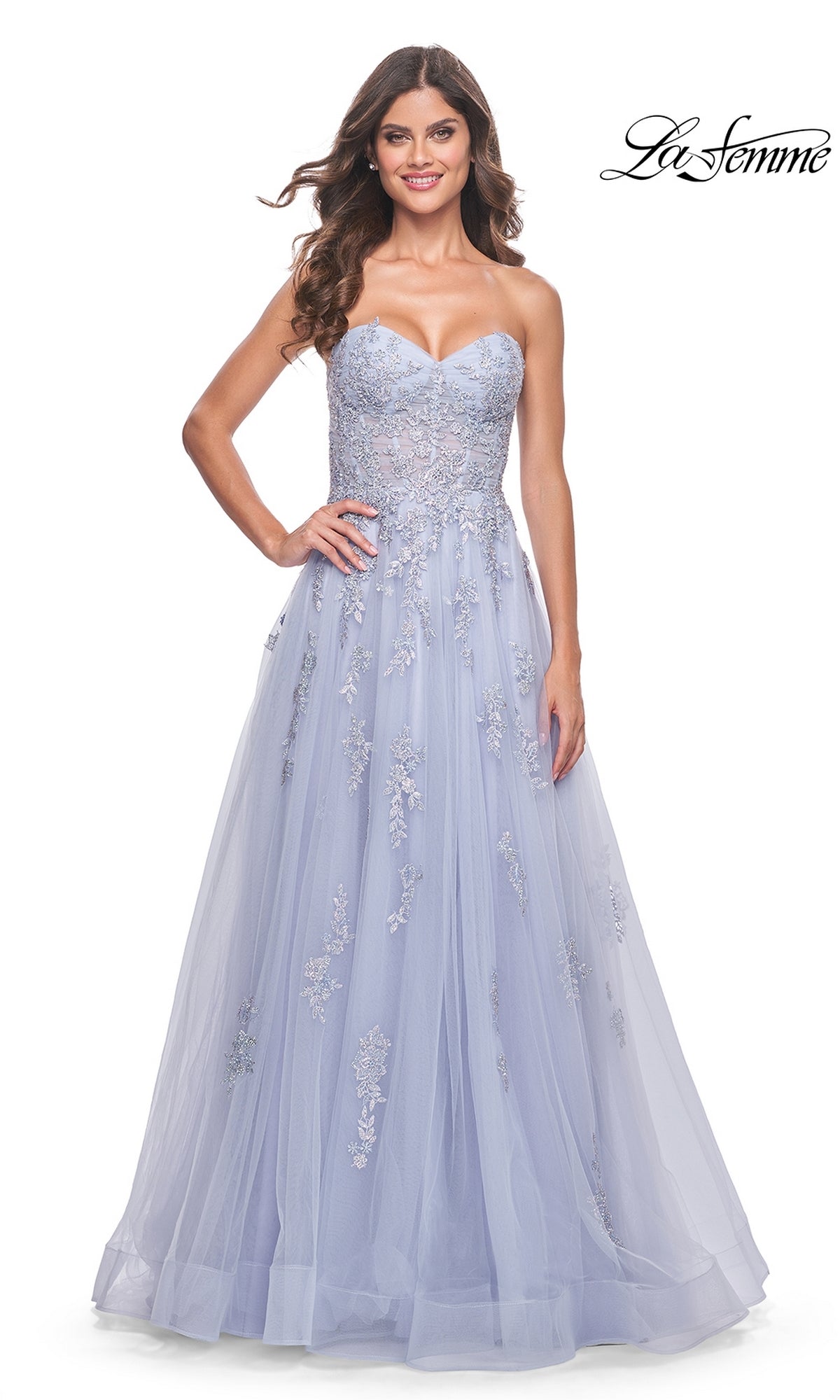A woman wears the La Femme Backless Strapless Long Prom Dress 32084, a lavender ball gown with floral embroidery. She stands facing forward and smiles, while the La Femme logo is displayed in the top right corner.