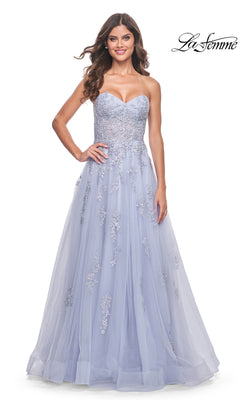 A woman wears the La Femme Backless Strapless Long Prom Dress 32084, a lavender ball gown with floral embroidery. She stands facing forward and smiles, while the La Femme logo is displayed in the top right corner.