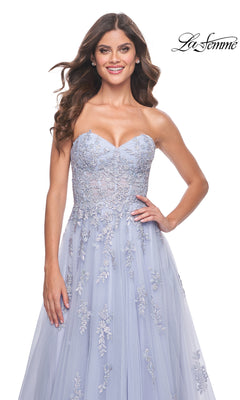 A woman in the La Femme Backless Strapless Long Prom Dress 32084, a light blue A-line gown with floral embroidery, stands against a white background. The La Femme logo appears in the top right corner.