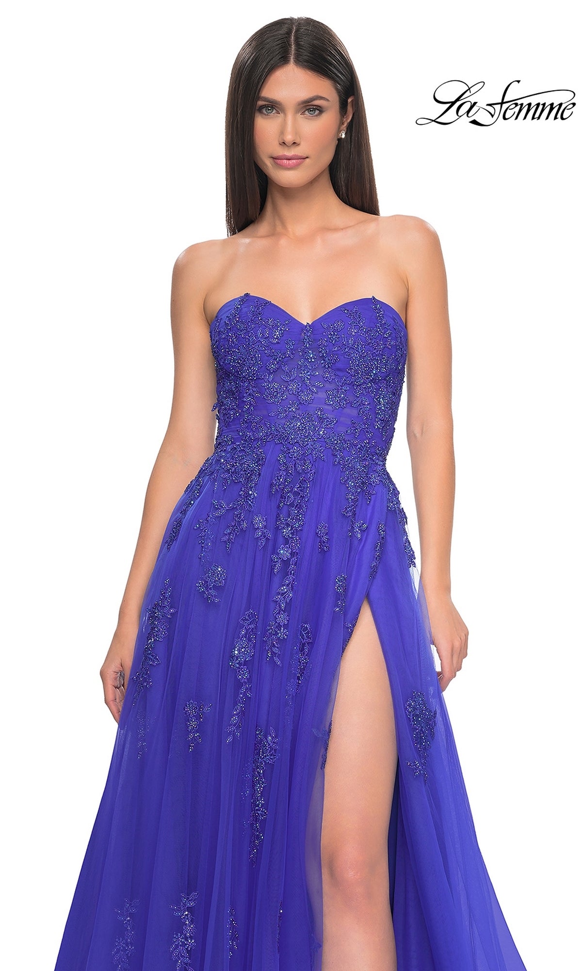 A woman models the La Femme Backless Strapless Long Prom Dress 32084—royal blue, floor-length, a-line with floral embellishments and a high slit—against a white background. 
