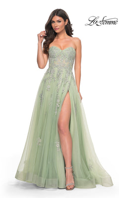 A woman wears the La Femme Backless Strapless Long Prom Dress 32084 in light green, featuring embellished details and a high slit, styled with silver heels, posing against a plain white background.