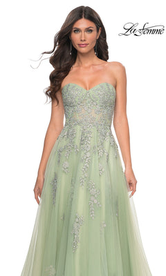 A woman models the La Femme Backless Strapless Long Prom Dress 32084 in light green with silver floral embroidery, standing against a white background. The La Femme logo appears at the top right.