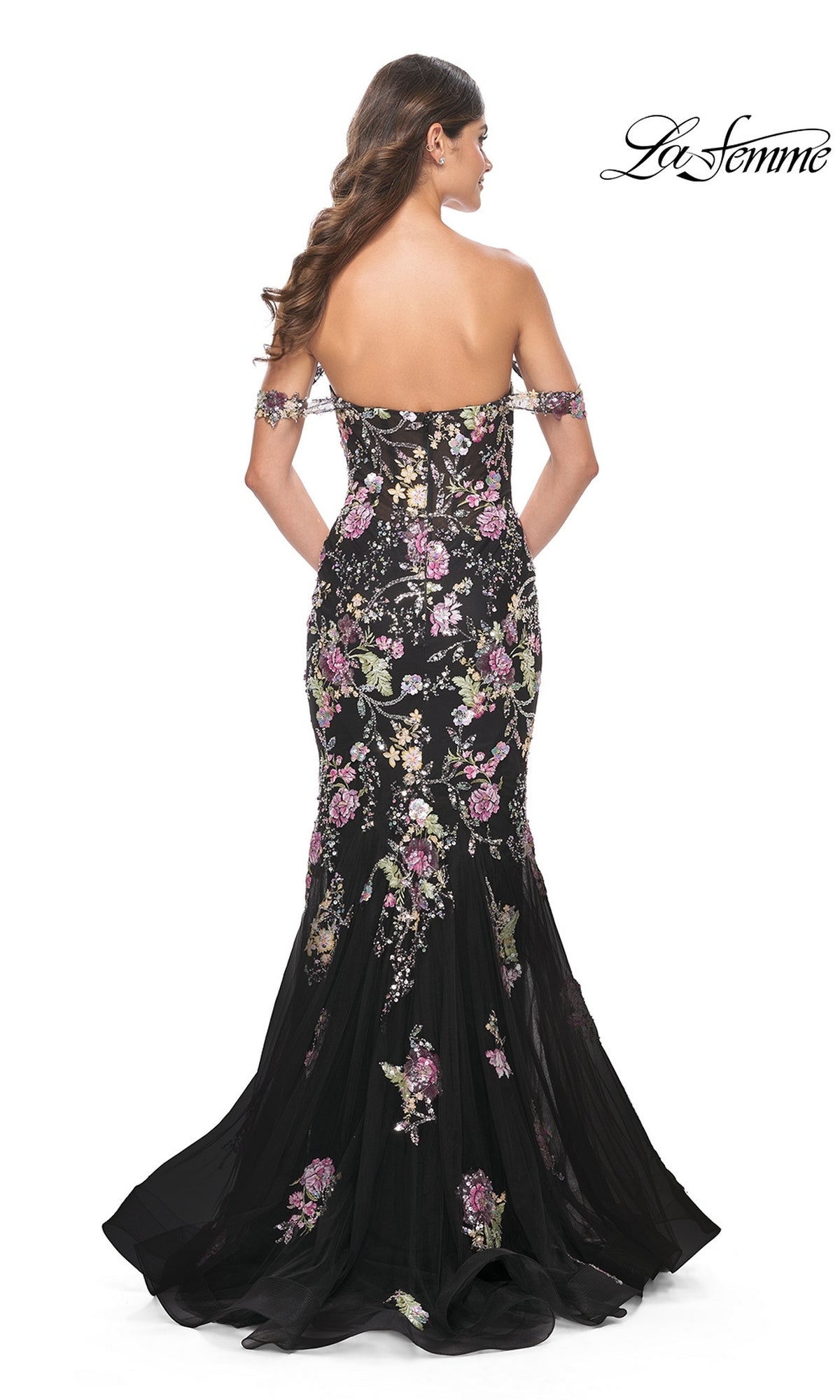 Woman in the La Femme Long Floral Mermaid Prom Dress 32087, a black floor-length off-the-shoulder gown with floral embroidery, shown from the back with loose wavy hair. 