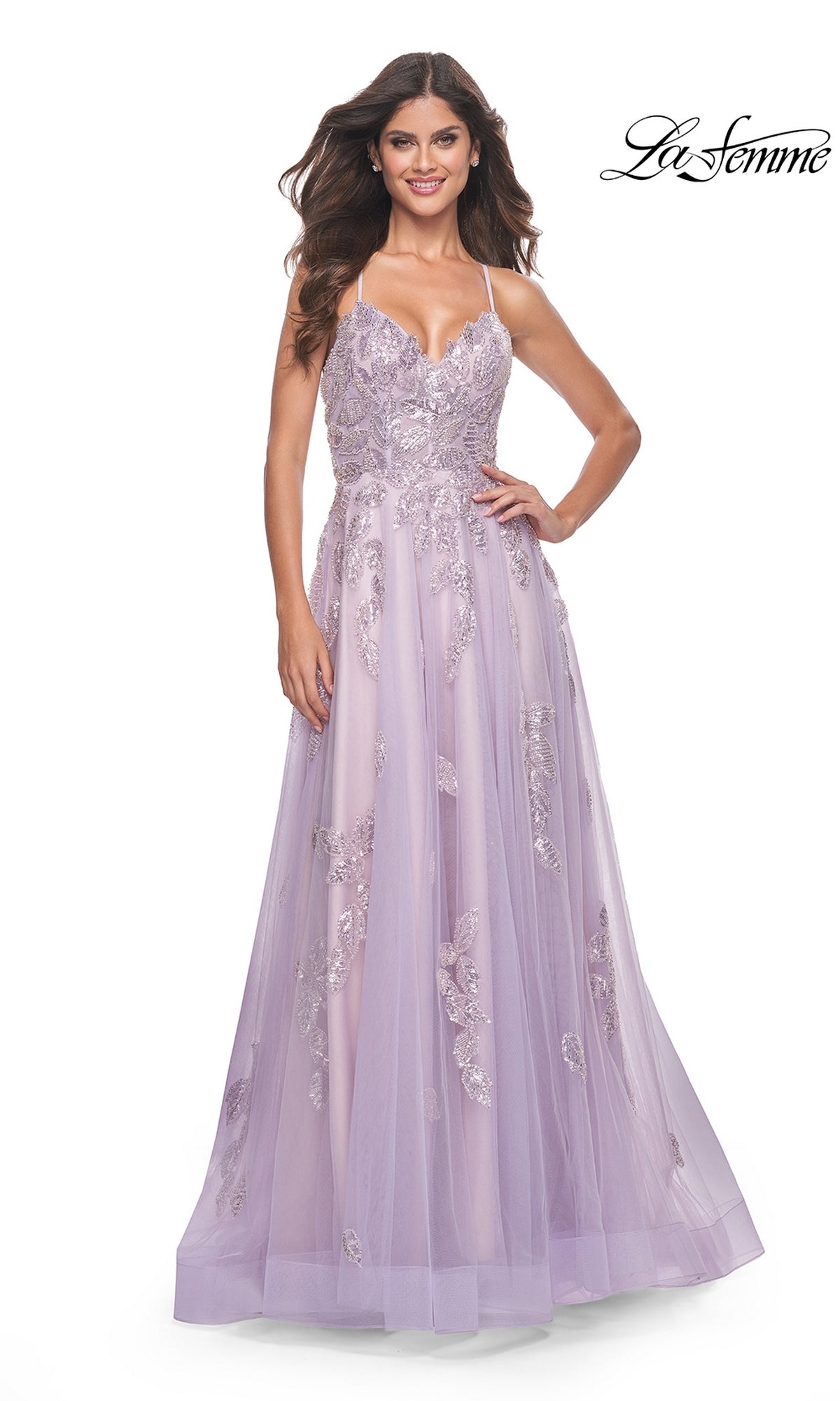 A woman stands smiling in the La Femme Sequin-Embroidered Long Prom Dress 32090—a lavender A-line gown with sequin embroidery and a tulle overlay.