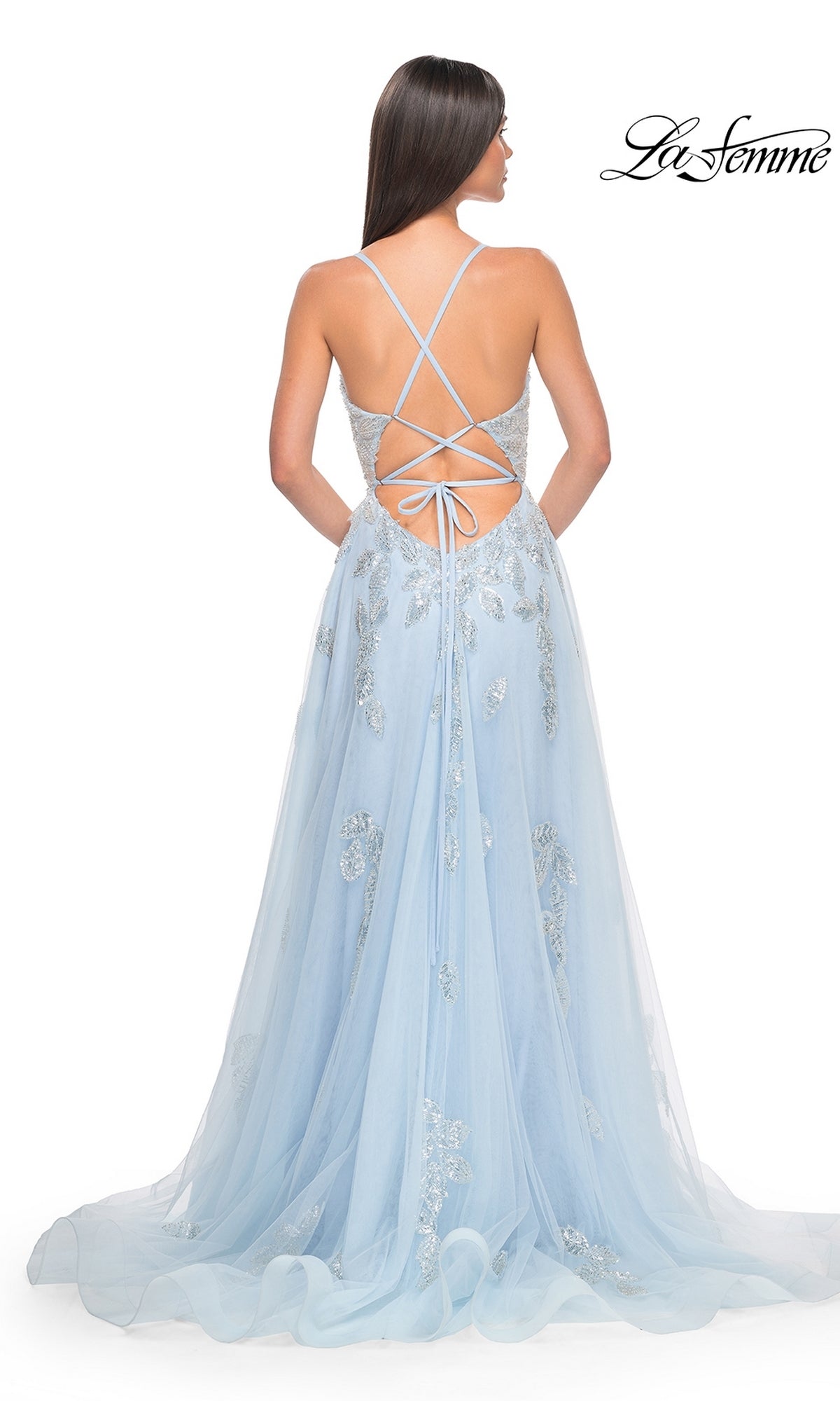 Woman in La Femme Sequin-Embroidered Long Prom Dress 32090, light blue with silver sequins, A-line silhouette, crisscross back straps, and a tie waist, shown from the back.