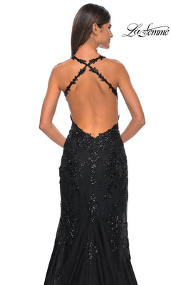 A woman wearing the La Femme Sequin-Tulle Long Prom Dress 32107 with crisscross straps and beaded details stands with her back to the camera. The "La Femme" logo is visible in the top right corner.