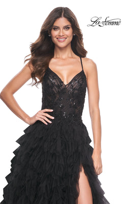 Model showcases the La Femme Long Black Ruffled Prom Ball Gown 32108 with spaghetti straps and sequin details, posing with one hand on her hip against a white background.