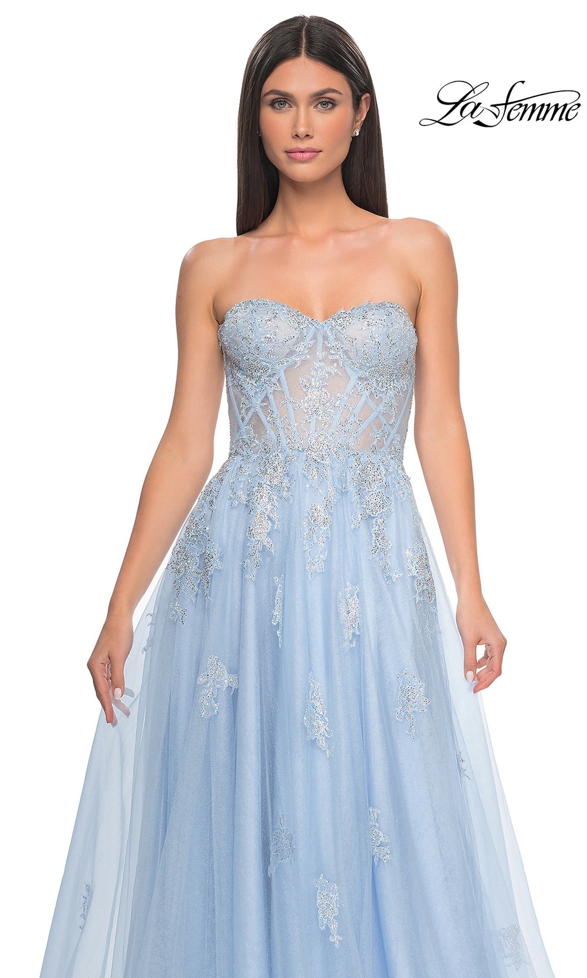 A woman models the La Femme Strapless Long A-Line Prom Dress 32111 in light blue with a sheer bodice and silver lace appliques, standing against a white background. The La Femme logo is visible in the top right corner.