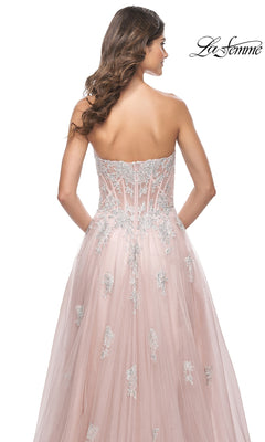 A woman is seen from the back wearing the La Femme Strapless Long A-Line Prom Dress 32111 with pink tulle, silver embroidery, a fitted corset-style bodice, embroidered lace appliques, and a flowing skirt.