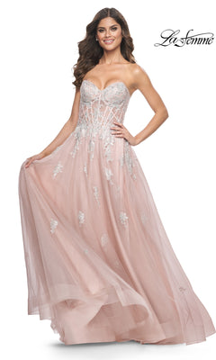 A woman wears the La Femme Strapless Long A-Line Prom Dress 32111 in blush pink, featuring silver embroidered lace appliques, a fitted bodice, and a flowing tulle skirt. The La Femme logo is shown in the top right corner.