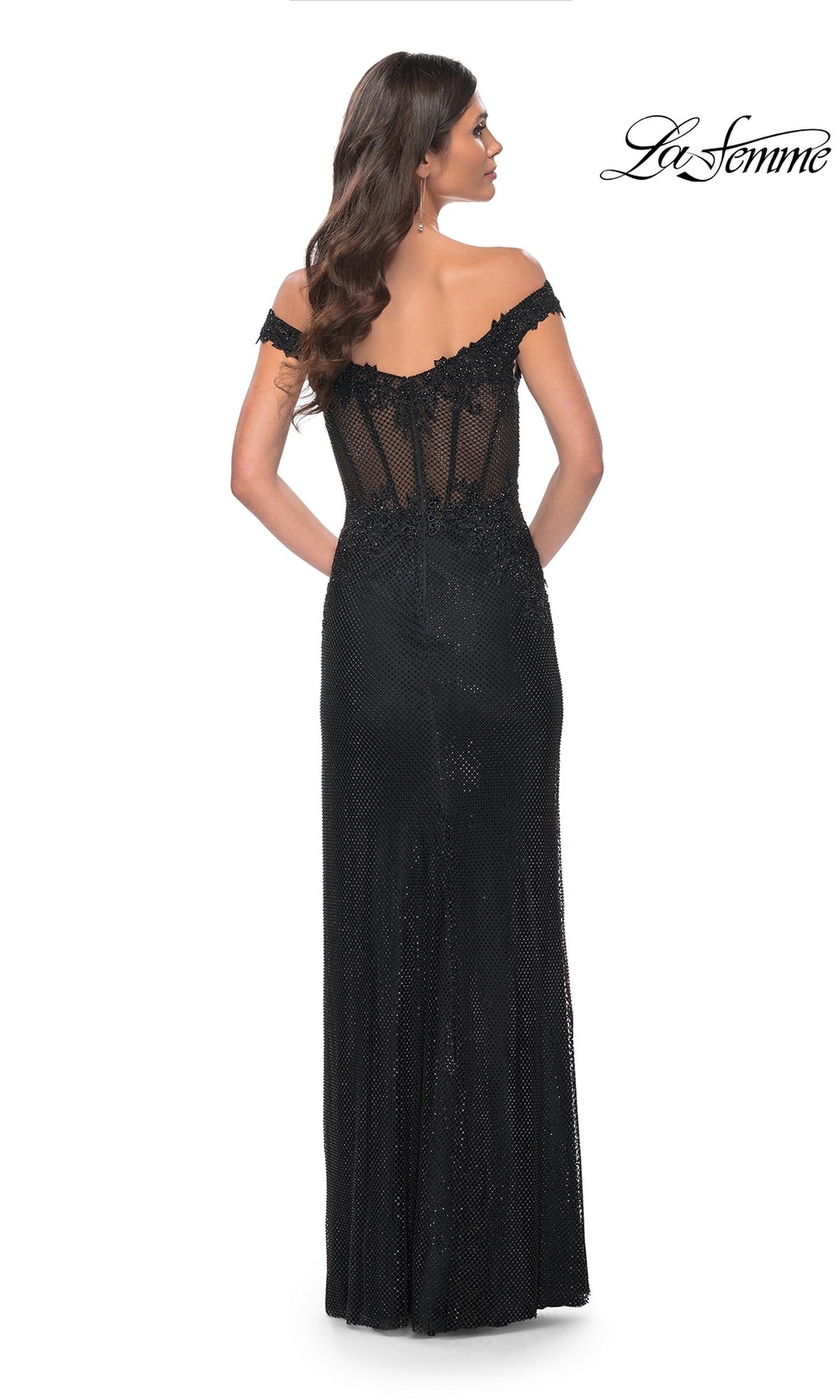 A woman faces away from the camera in the La Femme Off-Shoulder Long Corset Prom Dress 32116, featuring a sheer fitted corset bodice and lace back. The 