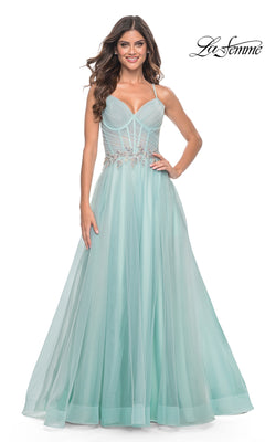 A woman wears the La Femme Sheer-Bodice Long A-Line Prom Dress 32117, a light blue, floor-length gown with thin straps, a fitted bodice, beaded waist detail, and a strappy open-back for an elegant modern look.