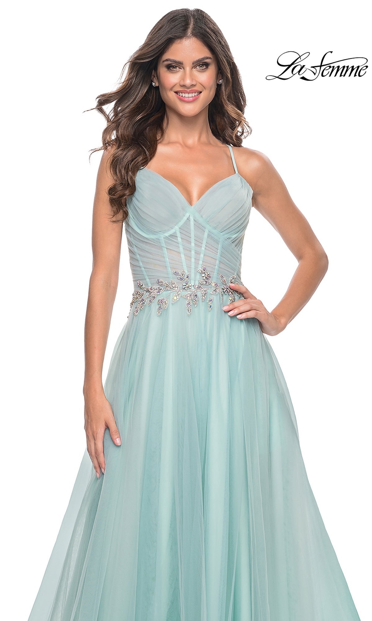 A woman wears the La Femme Sheer-Bodice Long A-Line Prom Dress 32117—a light blue, floor-length gown featuring beaded waist accents, sheer bodice detailing, and a strappy open-back design.