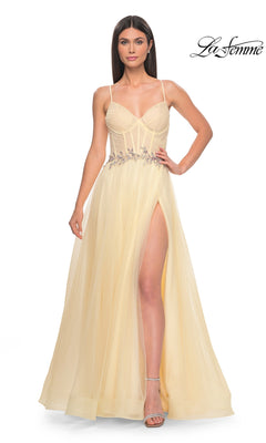 A woman in the La Femme Sheer-Bodice Long A-Line Prom Dress 32117, featuring thin straps, floral waist embellishments, a high slit, and a strappy open back for allure, stands against a white background.
