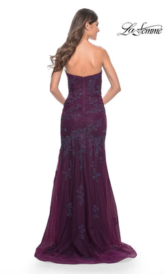A woman with long brown hair wears the La Femme Strapless Long Mermaid Prom Dress 32121 in deep purple, featuring floral embroidery, a fitted bodice, and a graceful floor-length train.