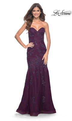 A woman poses in the La Femme Strapless Long Mermaid Prom Dress 32121— a dark berry, floor-length gown with floral embroidered lace—against a white background. The "La Femme" label appears in the top right corner.