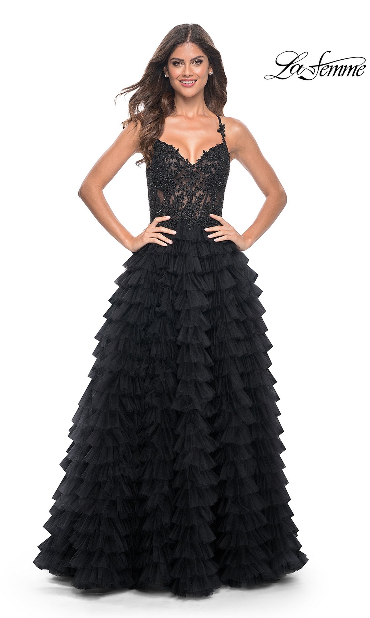 A woman stands against a white background wearing the La Femme Long Ruffled Prom Ball Gown 32128, featuring black lace and tulle, a fitted bodice, and a tiered ruffle skirt.