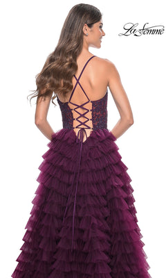 A woman stands with her back to the camera in the La Femme Long Ruffled Prom Ball Gown 32128, an elegant deep purple A-line dress featuring a lace-up back and a layered ruffled skirt.