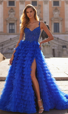 A woman in the La Femme Long Ruffled Prom Ball Gown 32128, a vibrant blue dress with a thigh-high slit, poses outdoors on stone steps before a historic building.