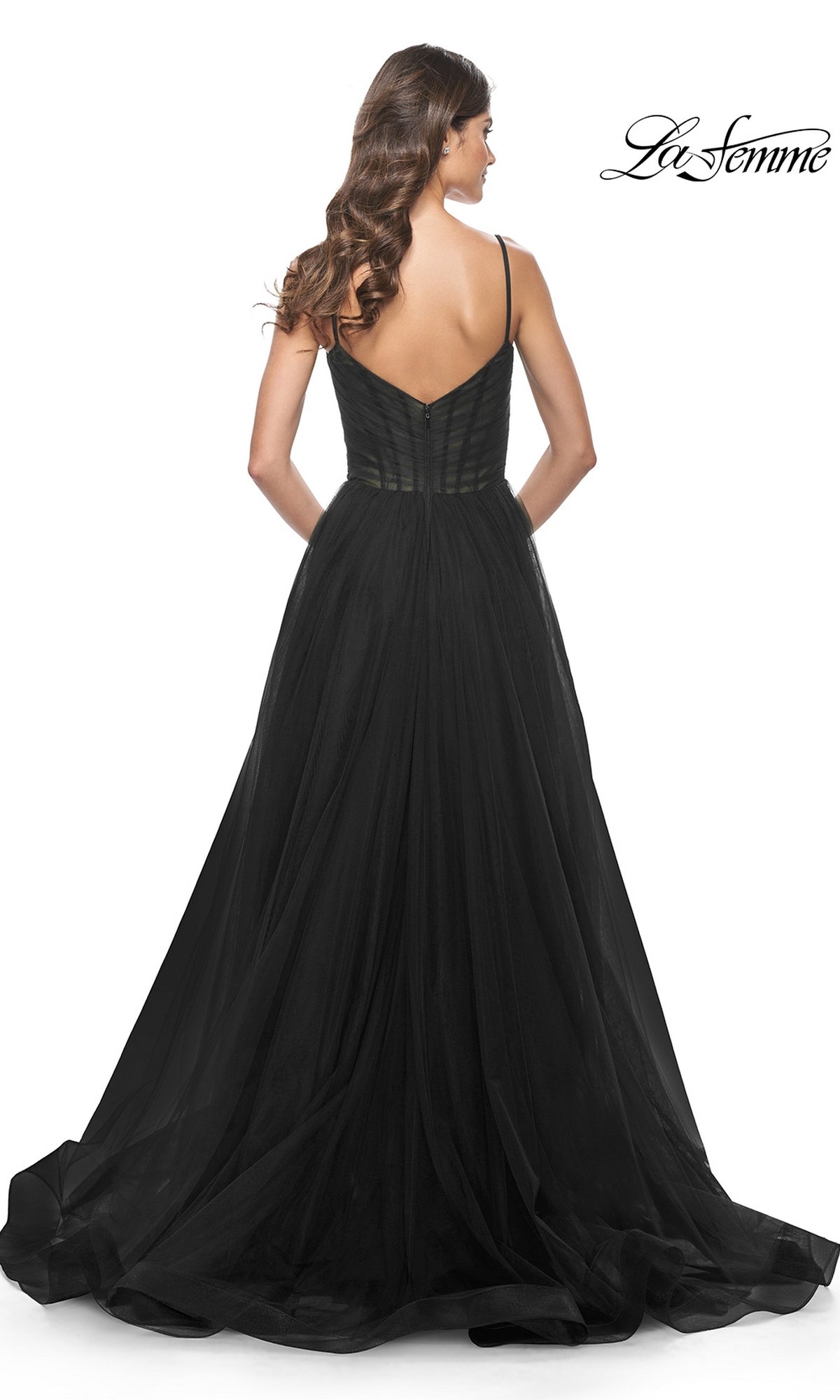A woman with wavy hair models the La Femme Sheer-Waist Long A-Line Prom Dress 32130, featuring a fitted bodice and flared tulle skirt, elegantly photographed from the back.