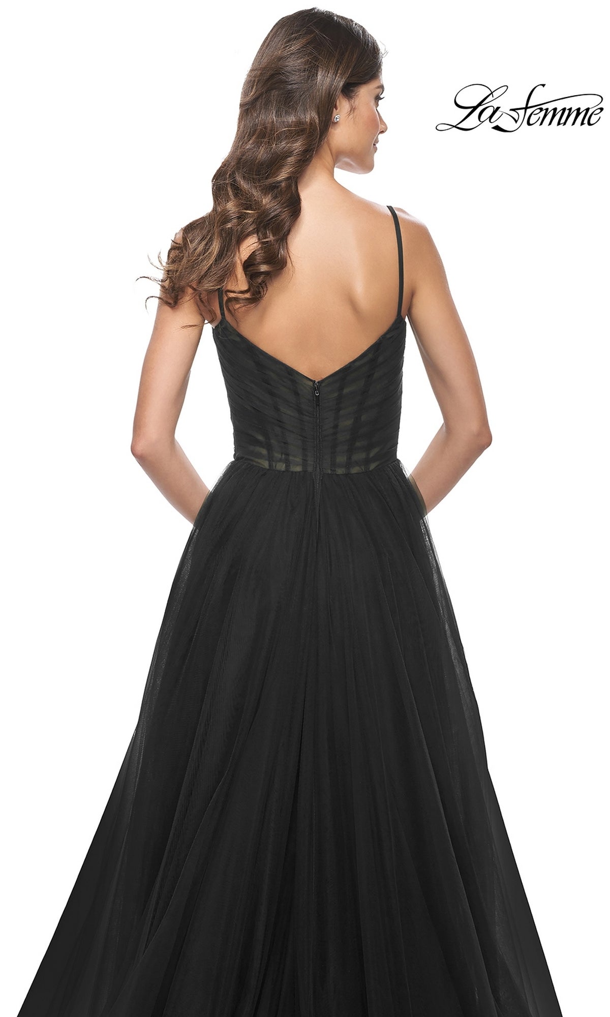 Woman with long, wavy brown hair wears a black La Femme Sheer-Waist Long A-Line Prom Dress 32130 with thin straps and a V-shaped back. 