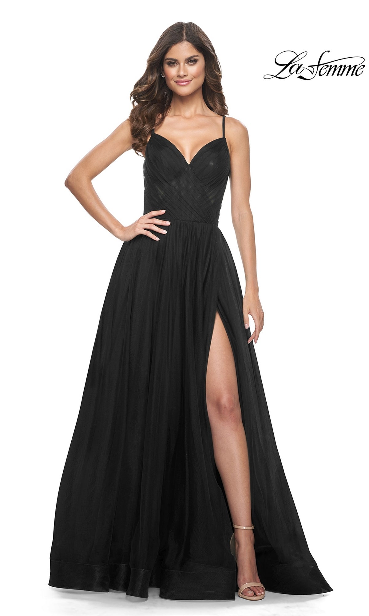 Woman in La Femme Sheer-Waist Long A-Line Prom Dress 32130—sleeveless, black, with a sweetheart neckline and thigh-high slit—stands smiling against a white background. 