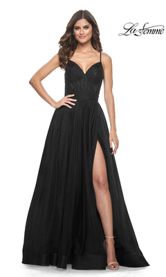 Woman in La Femme Sheer-Waist Long A-Line Prom Dress 32130—sleeveless, black, with a sweetheart neckline and thigh-high slit—stands smiling against a white background. "La Femme" logo appears in the top right corner.